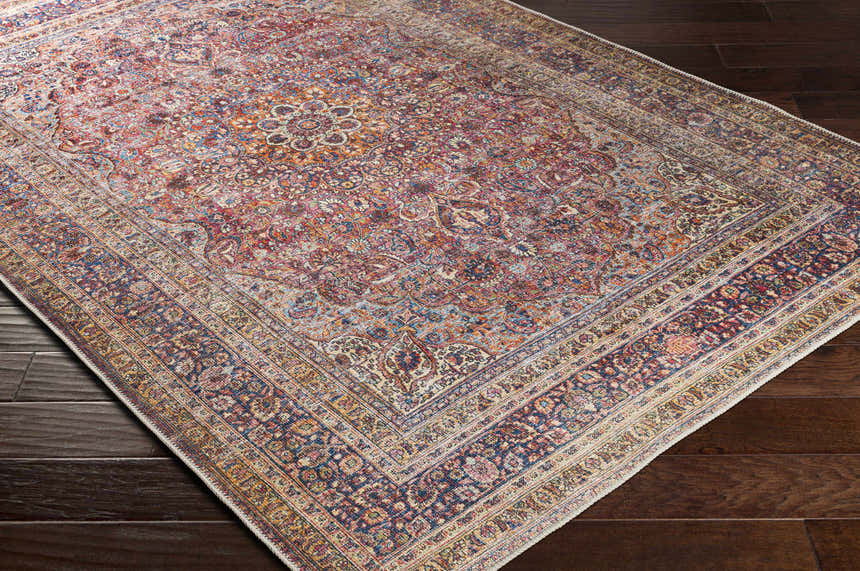 Close-up of the Belison Washable Area Rug showing its traditional floral pattern and rich colors on a dark wood floor. Corner