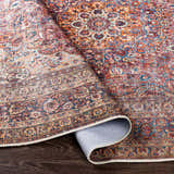 Close-up of the Belison Washable Area Rug showing its traditional floral pattern in orange, red, and blue hues. Fold
