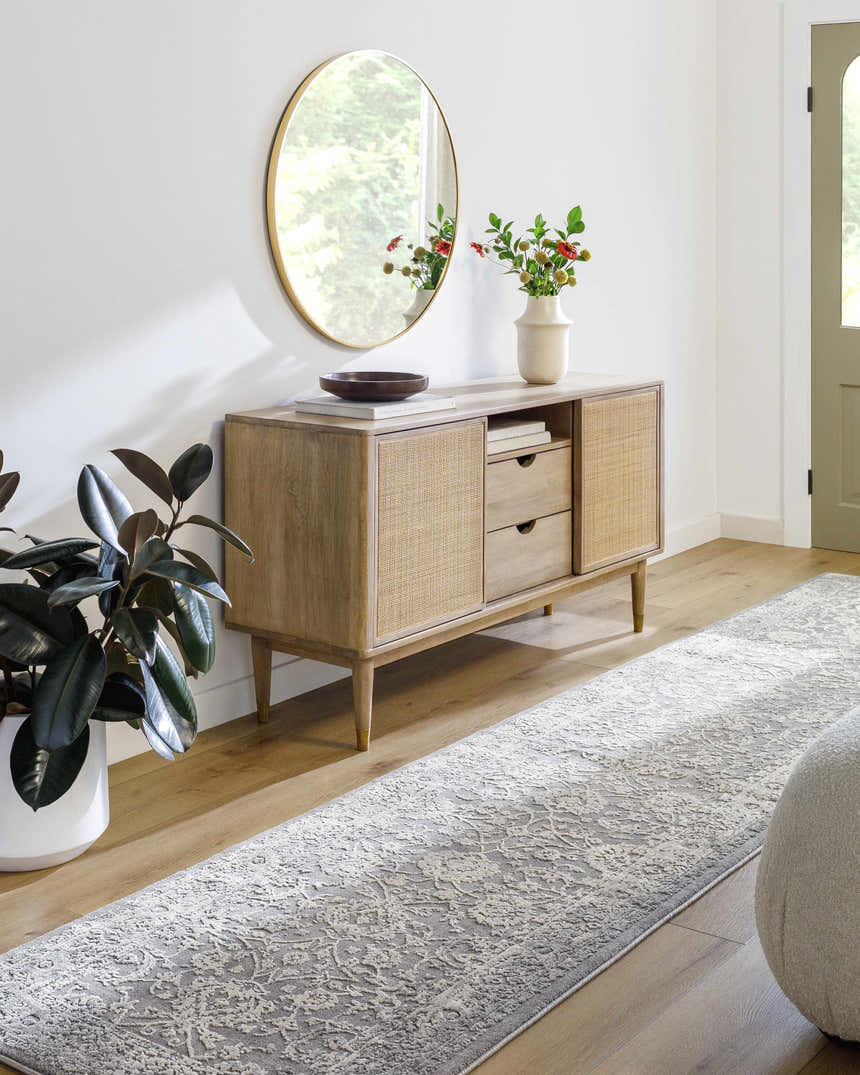 Entryway scene with a gray and ivory Benavides Gray Updated Traditional Tibetan Rug runner, wood console table, and round gold mirror. Roomscene-Runner