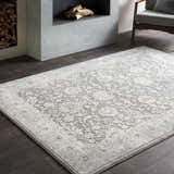 Living room scene with a gray Benavides Gray Updated Traditional Tibetan Rug, fireplace, and gray chair. Roomscene-Rectangle