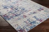 Close-up of the Bergvliet Area Rug. Contemporary style with blue, burgundy, cream, and light gray abstract pattern. Corner