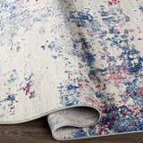 Close-up of the Bergvliet Area Rug showing its cream base with blue and burgundy contemporary abstract pattern. Fold