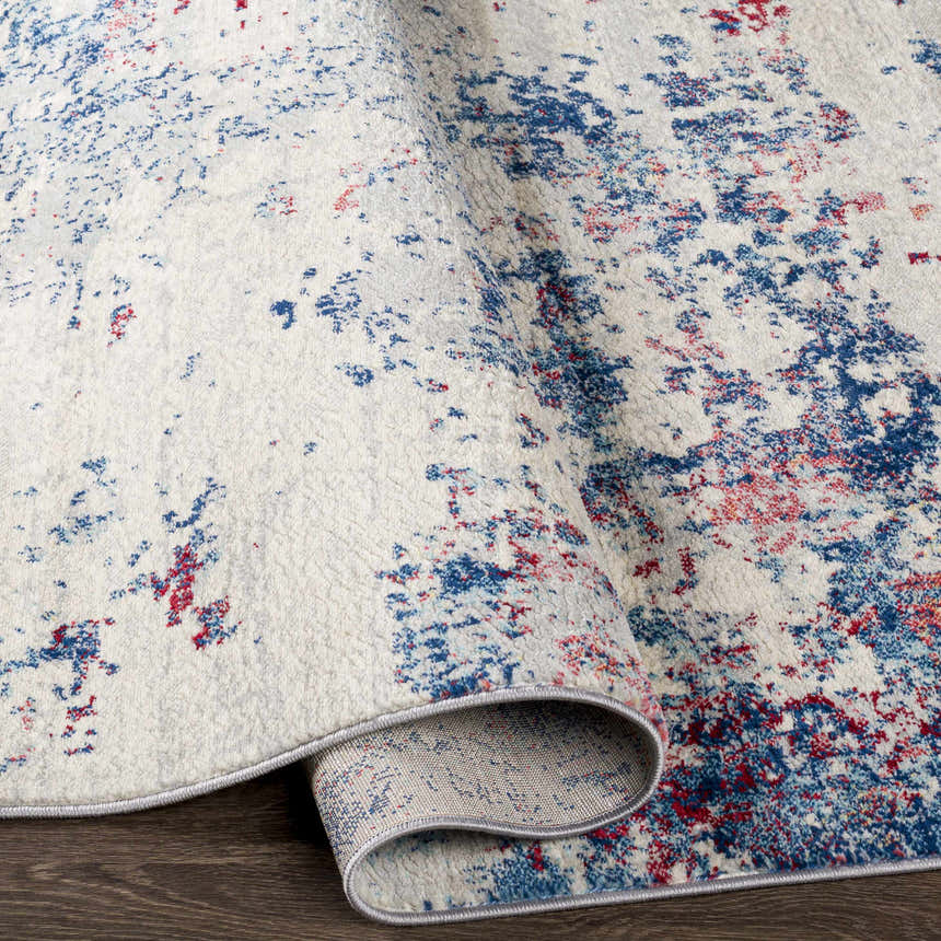 Close-up of the Bergvliet Area Rug showing its cream base with blue and burgundy contemporary abstract pattern. Fold