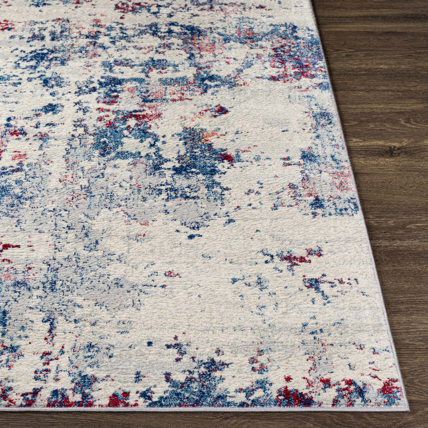 Close-up of the Bergvliet Area Rug showing its cream base with blue and burgundy abstract pattern on a dark wood floor. Front