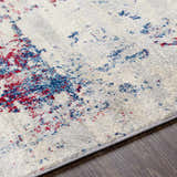 Close-up of the Bergvliet Area Rug: cream rug with blue and burgundy contemporary pattern on dark wood floor. Texture