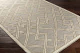 Close-up of the Bevier Area Rug. Hand-woven viscose rug in dusty sage and light gray with a geometric pattern. Corner