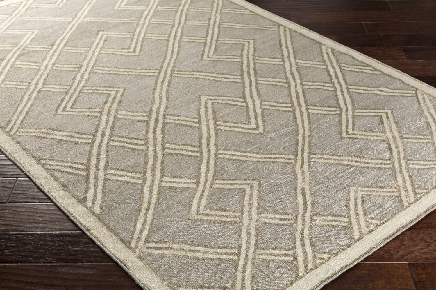 Close-up of the Bevier Area Rug. Hand-woven viscose rug in dusty sage and light gray with a geometric pattern. Corner