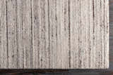 Close-up of the hand-loomed Beykoz Area Rug. Cream and light beige rug with dark brown vertical stripes. Contemporary style. Corner