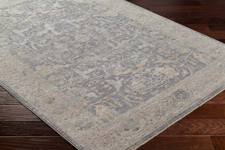 Close-up of Binx Thick Luxe Statement Rug. Farmhouse style rug in brown, charcoal, dusty sage, gray and teal on wood floor. Corner