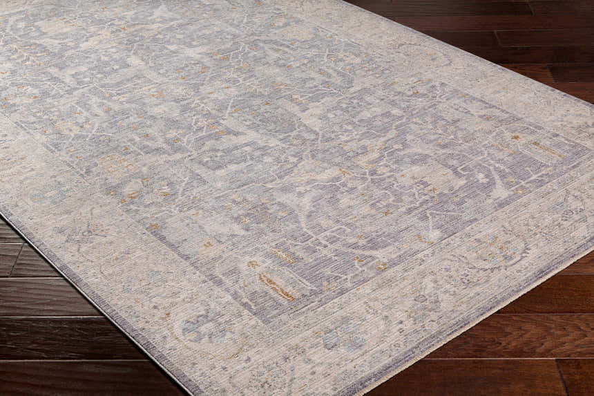 Close-up of Binx rug showing traditional pattern in brown, charcoal, dusty sage, medium gray, and teal on dark wood floor. Corner
