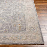 Close-up of Binx Thick Luxe Statement Rug showing traditional pattern, brown, charcoal, sage and gray colors on wood floor. Front