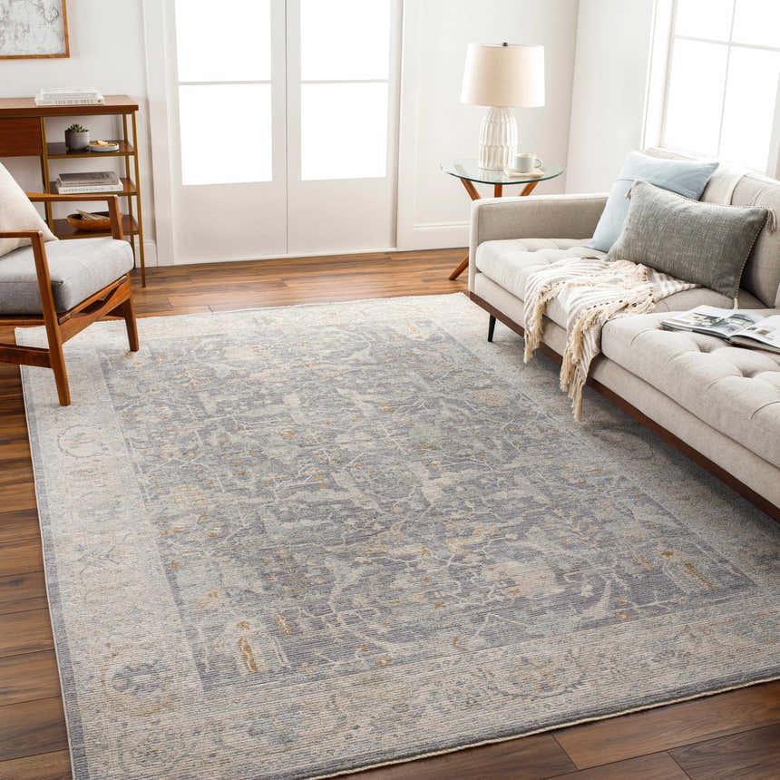 Living room scene with a gray sofa and the Binx Thick Luxe Statement Rug in brown, charcoal, dusty sage, medium gray, and teal. Roomscene-Rectangle