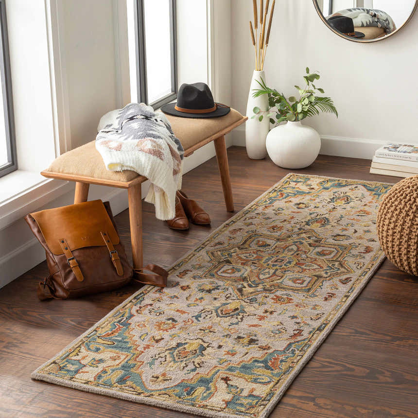 Entryway scene with Birtley Area Rug, a vintage style runner with blue, tan, and rust hues, paired with a wood bench and woven pouf. Roomscene-Runner