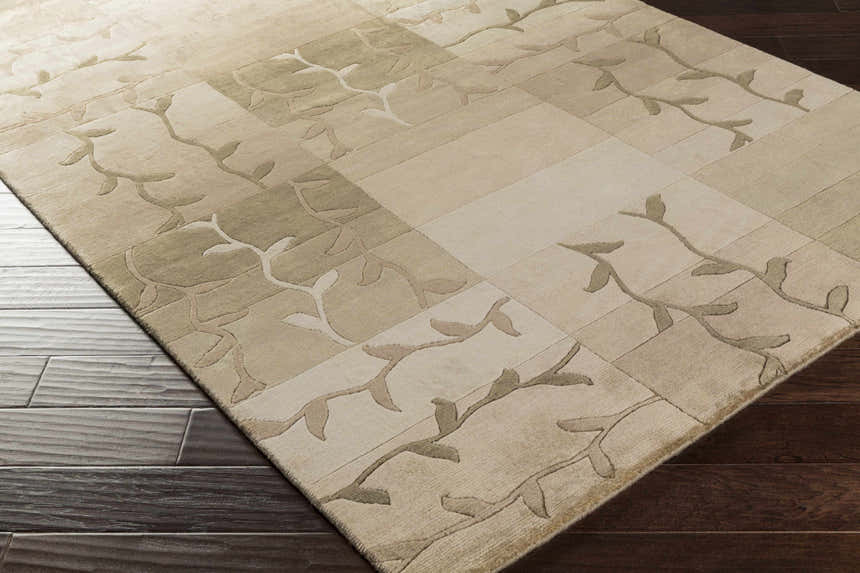 Close-up of Bissell Area Carpet. Hand-knotted wool rug in dark brown, light brown, and off-white with a contemporary leaf pattern. Corner