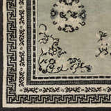 Close up of the hand knotted wool Bixby Area Rug featuring a traditional floral design in black, sage, and light beige. Swatch