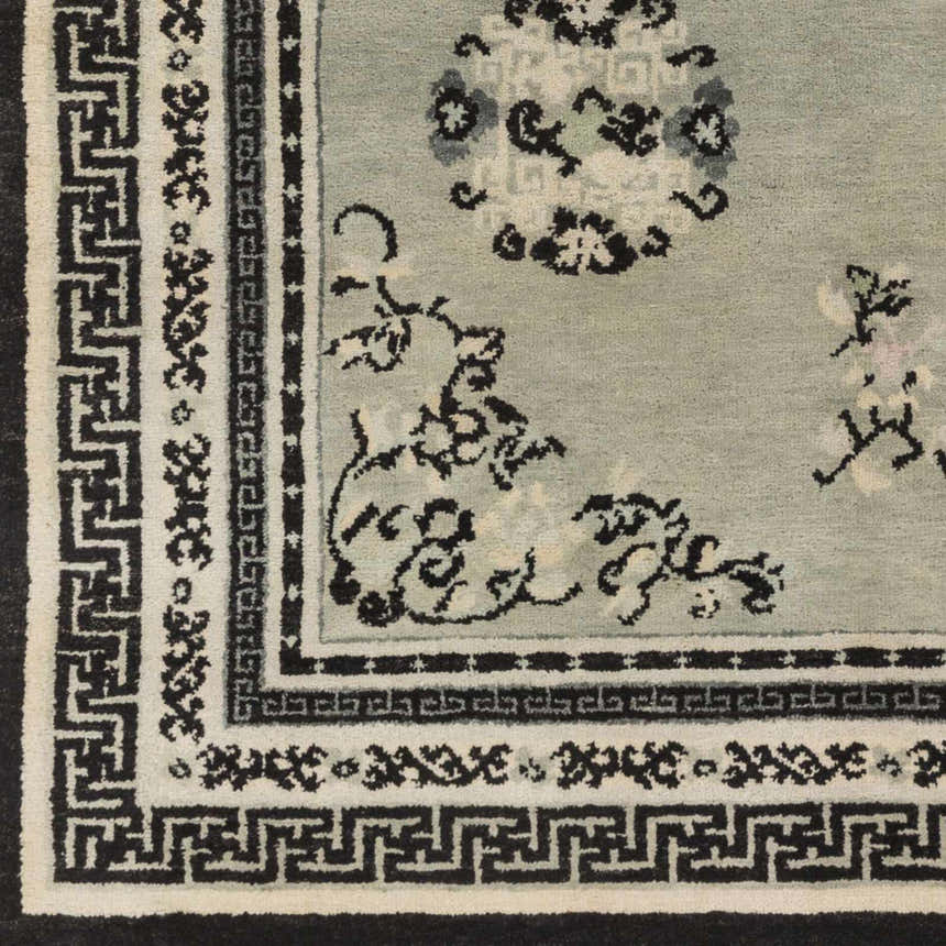 Close up of the hand knotted wool Bixby Area Rug featuring a traditional floral design in black, sage, and light beige. Swatch
