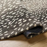 Close up of the Athena Giraffe Print Wool Rug showing the beige and charcoal tones and hand tufted texture. Fold