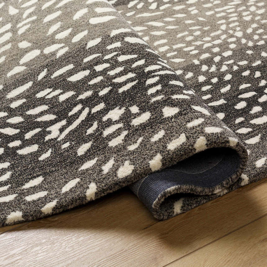 Close up of the Athena Giraffe Print Wool Rug showing the beige and charcoal tones and hand tufted texture. Fold