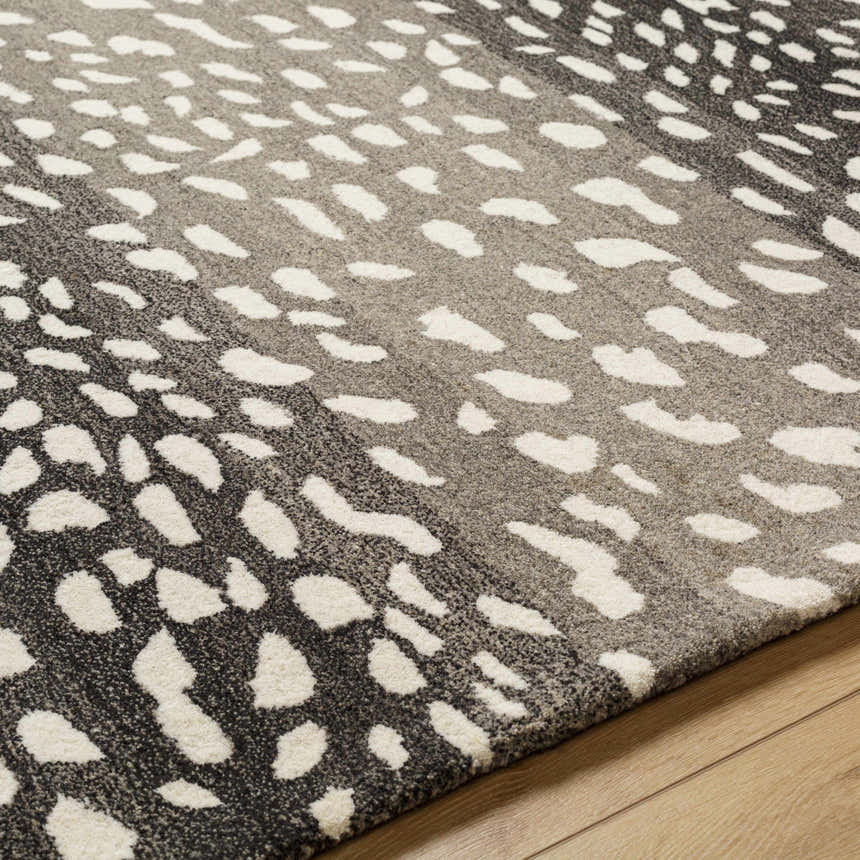 Close-up of the Athena Giraffe Print Wool Rug, showing the beige, charcoal, and white thatch colors and textured, hand-tufted wool. Texture