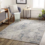 Living room scene with a gray chair and the Balasing Area Rug in dark gray, ivory, and blue tones. Roomscene-Rectangle