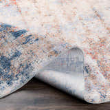 Close up of the Bonaventure Area Rug showing charcoal, red, gray, and navy abstract pattern and machine woven texture. Fold