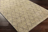 Close-up of the hand-loomed Bonogin Area Rug. Dark brown geometric pattern on a tan and olive viscose rug. Corner