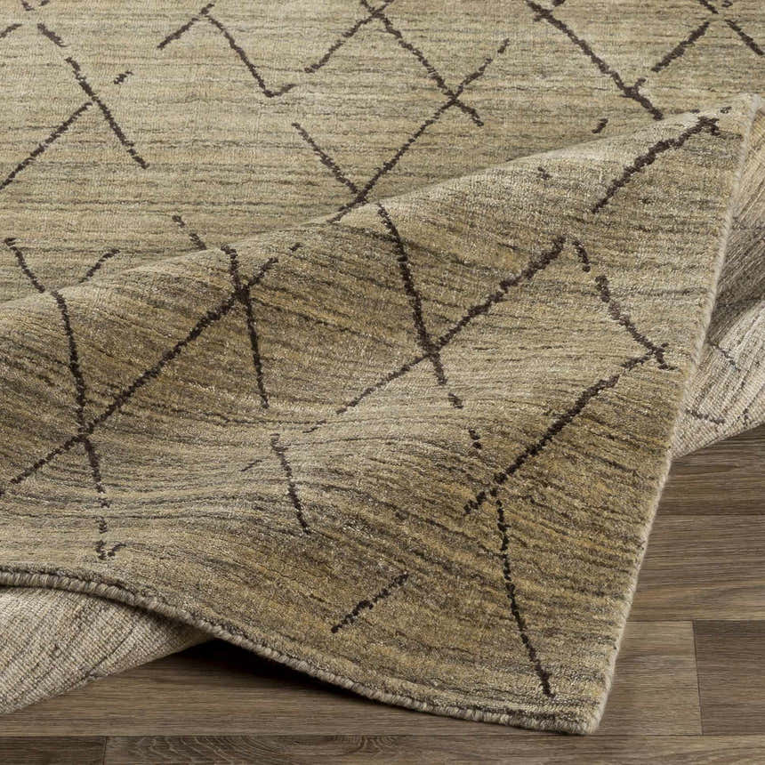 Close-up of the Bonogin Area Rug showing its tan and olive colors and dark brown geometric diamond pattern. Fold