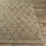 Close-up of the Bonogin Area Rug showing its tan color and dark brown geometric diamond pattern on wood floors. Front