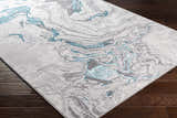 Close-up of the Bonville Blue Marble Rug. Features a contemporary marble-like pattern in blue, cream, beige, and gray. Corner
