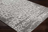 Close-up of the Bowden Carpet - Clearance. Charcoal, light gray, and white floral pattern rug on dark wood floor. Corner