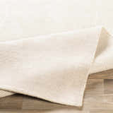 Close-up of the cream and taupe Bowstring Carpet showing its hand-loomed texture and construction. Fold