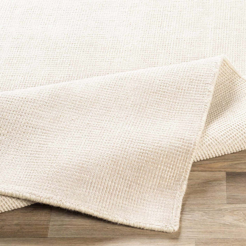 Close-up of the cream and taupe Bowstring Carpet showing its hand-loomed texture and construction. Fold