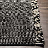 Close-up of the hand-woven Boyden Black Area Rug with Tassels, showing its black and cream yarn texture. Front