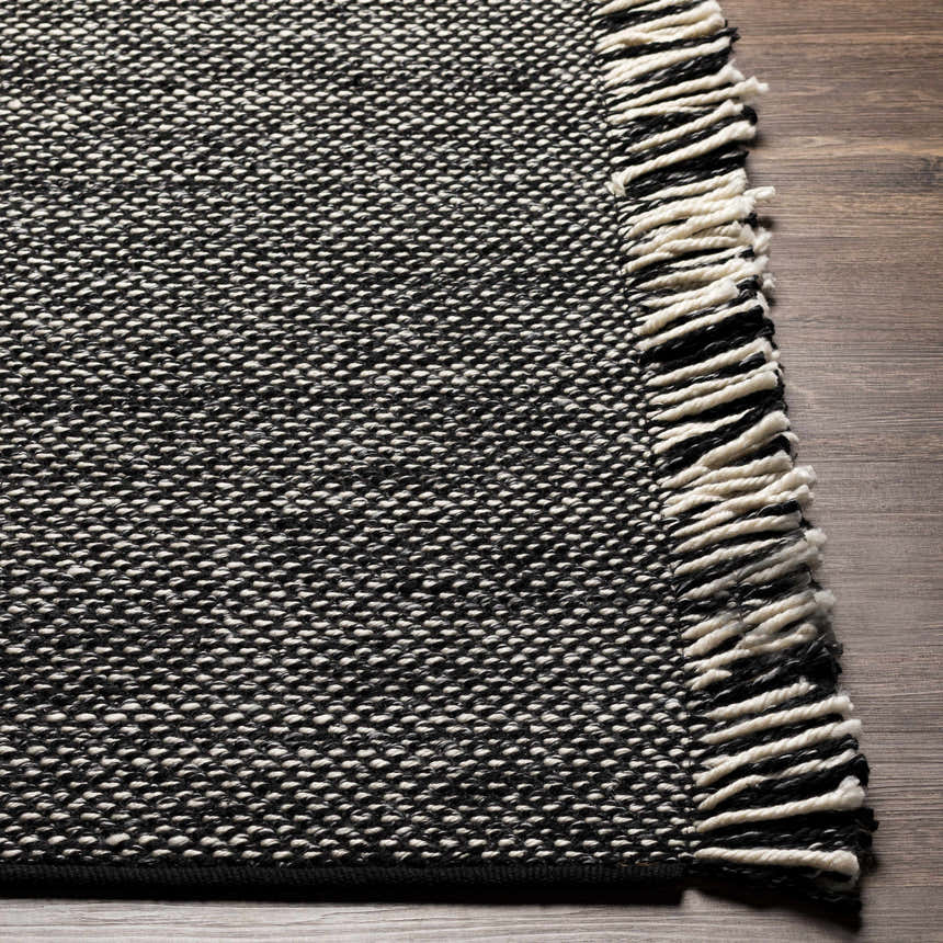 Close-up of the hand-woven Boyden Black Area Rug with Tassels, showing its black and cream yarn texture. Front