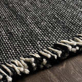 Close-up of the textured Boyden Black Area Rug with Tassels, showing the black and cream woven design. Texture