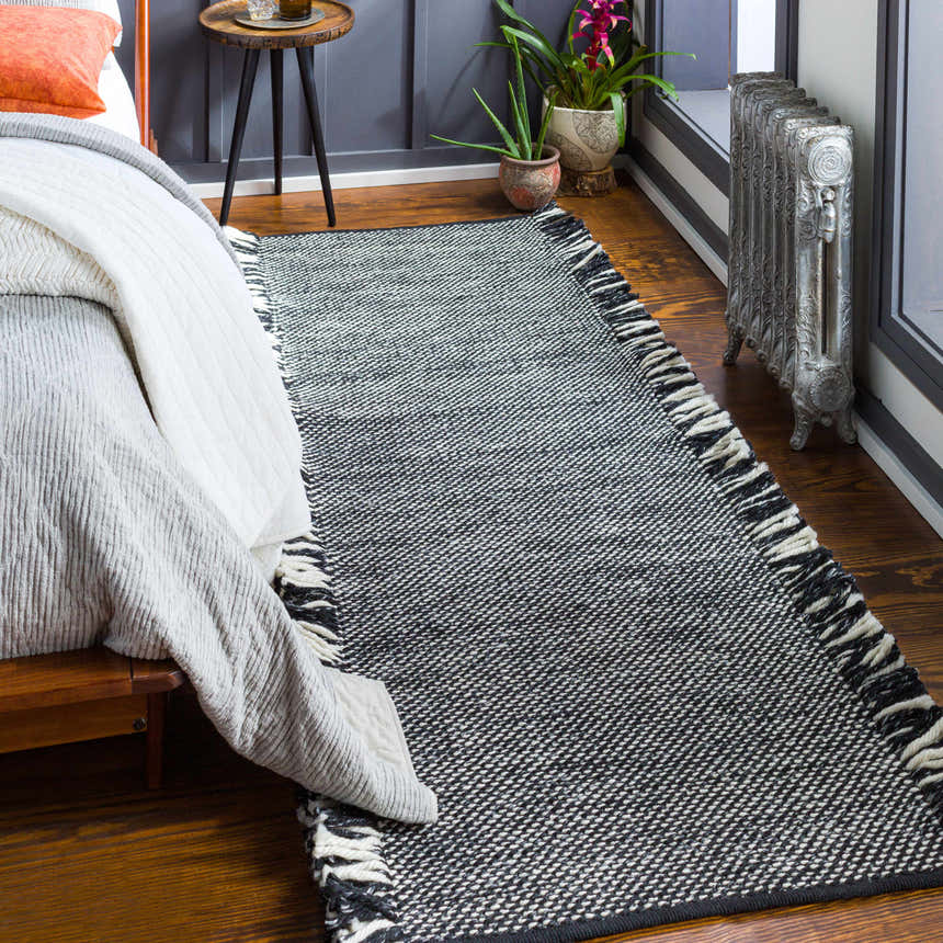 Bedroom scene with Boyden Black Area Rug. Contemporary rug with tassels, black and cream colors, on hardwood floor. Roomscene-Runner