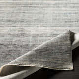 Braxton Carved Statement Area Rug close-up. Abstract design in gray, ivory, and charcoal. Machine woven texture. Fold