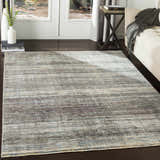 Living room scene with Braxton Carved Statement Area Rug in blue, gray, and ivory tones on dark wood floors. Roomscene-Rectangle