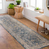 Entryway with a blue and beige Barcelona Luxe Performance Rug runner, wood floors, bench, and plants. Roomscene-Runner