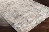 Close-up of the Braddyville Area Rug, a contemporary rug in cream, gray, black, and brown, on a dark wood floor. Corner
