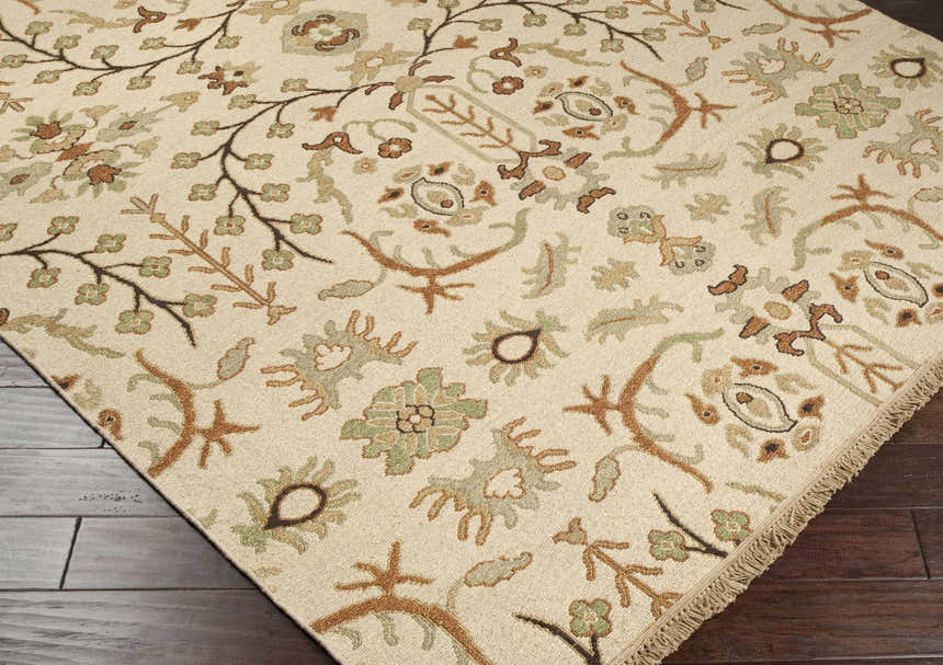 Close-up of the Brentford Carpet showing its traditional floral pattern in oatmeal, olive, brown, and tan on a dark wood floor. Corner
