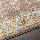 Close-up of the Bourget Area Carpet showing a traditional, floral pattern in cream, gray, mustard, and blue on dark wood flooring. Texture