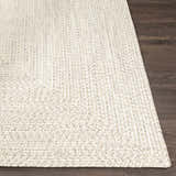 Close-up of Beige Braided Faux Jute Rug showing the braided texture and neutral colors on a dark wood floor. Front