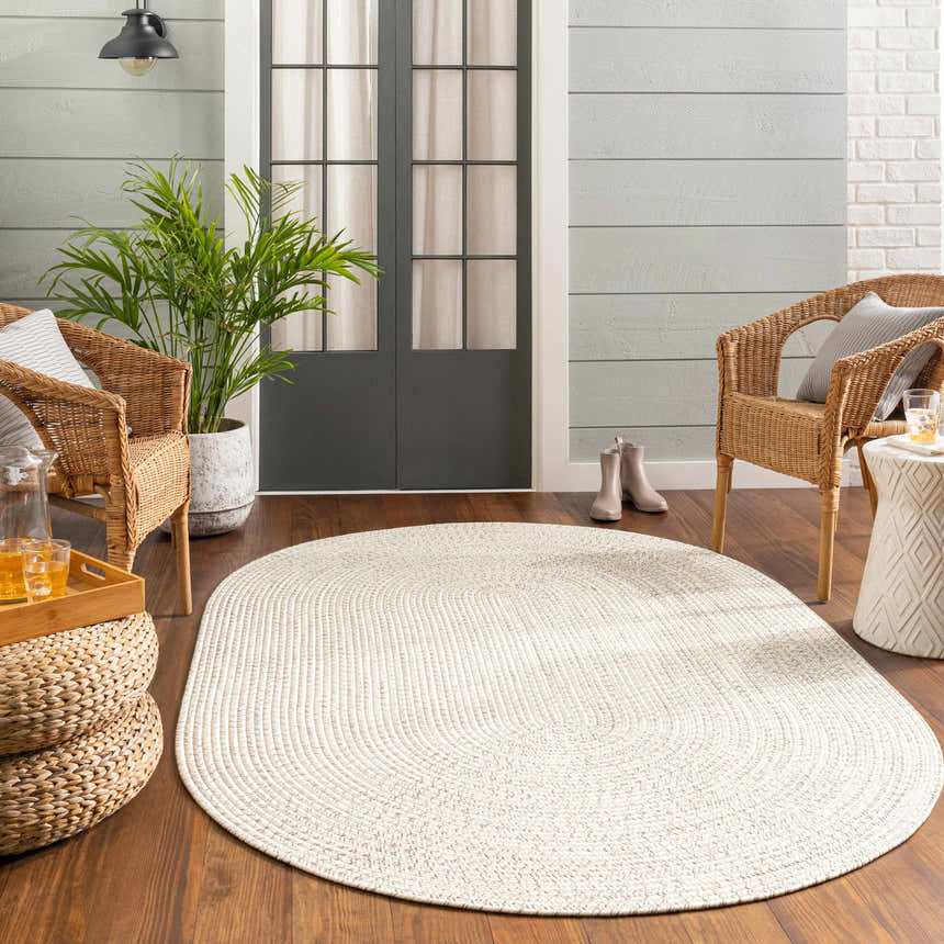 Cozy porch scene with a beige braided faux jute rug, wicker chairs, and wood accents. Roomscene-Oval