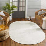 Cozy porch scene with an oval Beige Braided Faux Jute Rug, wicker chairs, and wood floors. Roomscene-Oval