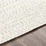 Close-up of a Beige Braided Faux Jute Rug showing its woven texture and neutral colors on a dark wood floor. Texture