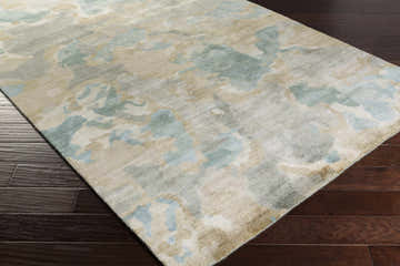 Close-up of Briceville Premium Area Rug showing ivory, green, blue, peach, and wheat abstract pattern on dark wood floor. Corner