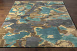 Close-up of Briceville Premium Area Rug with abstract ivory, green, blue, peach, and wheat pattern on a dark wood floor. Front