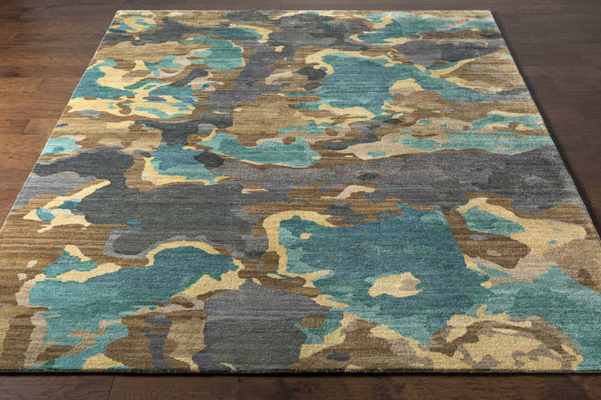 Close-up of Briceville Premium Area Rug with abstract ivory, green, blue, peach, and wheat pattern on a dark wood floor. Front