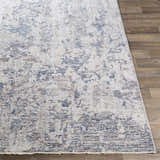 Close-up of the Broxbourne Area Rug. Contemporary design in blush, brown, cream, and navy on a wood floor. Front